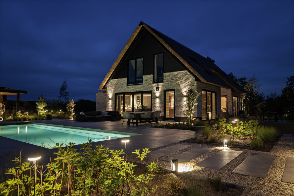 Tuin met moderne verlichting en strakke afwerking, gecreëerd door De Gaarde Hoveniers voor een sfeervolle uitstraling.