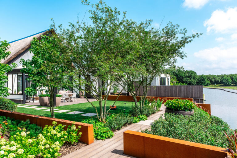 Een strak ontworpen tuin met houten elementen en verzorgde beplanting, perfect onderhouden door De Gaarde Hoveniers.